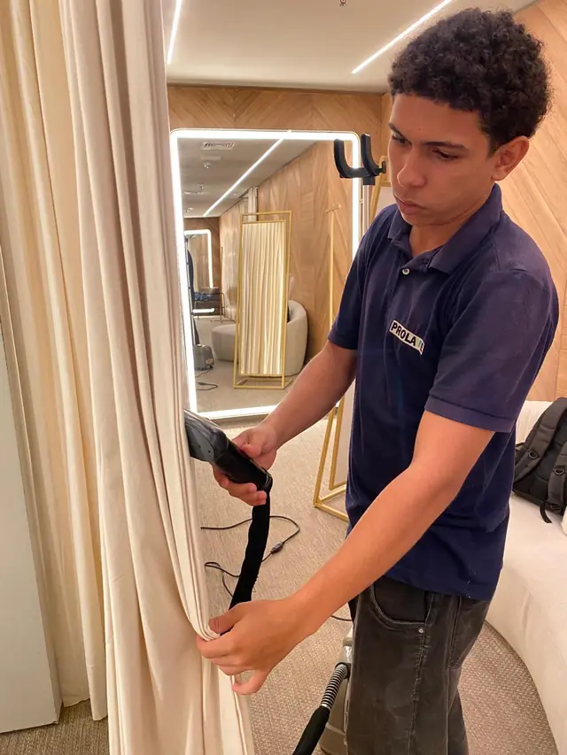 Profissional da PROLAVE higienizando uma cortina de tecido com equipamento de extração