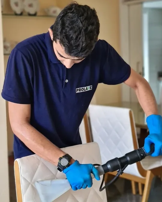 Profissional da PROLAVE higienizando o estofado de uma cadeira com equipamento de extração