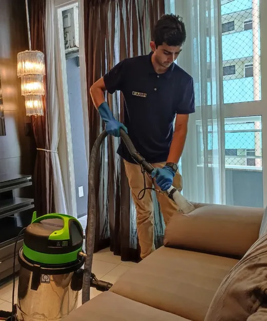 Técnico da PROLAVE higienizando um sofá com extratora profissional na sala do cliente